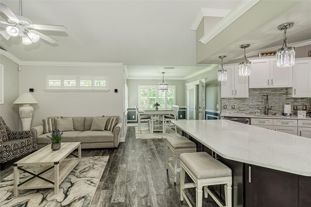 A kitchen with a large island and stools opens into a living room and dining area — 5864 MANCHESTER DRIVE W, LAKELAND, FL