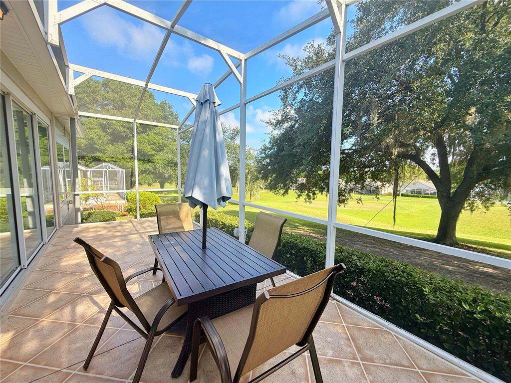 A screened-in patio features a dining set, tile flooring, and a view of a golf course — 2222 CAXTON AVENUE, CLERMONT, FL