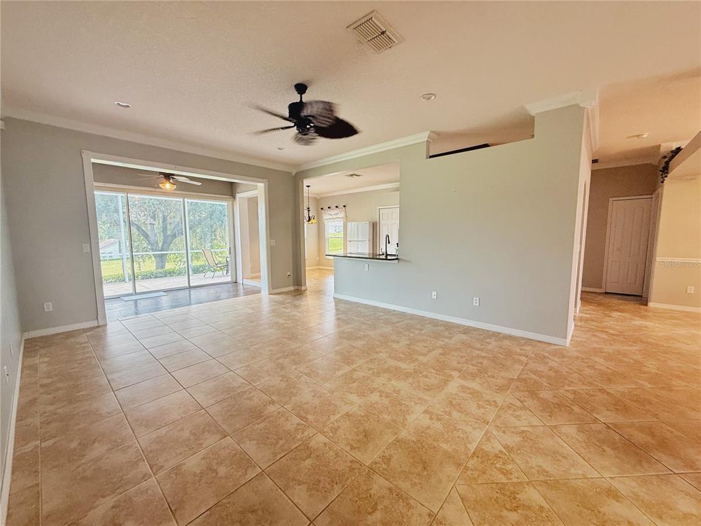 An open-concept living area with tile flooring, a ceiling fan, and a sliding glass door — 2222 CAXTON AVENUE, CLERMONT, FL