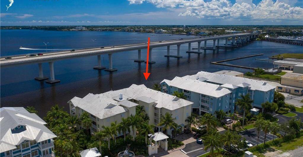 An aerial view shows a multi-story waterfront apartment complex next to a long bridge — 275 NW Flagler Avenue # 205, Stuart FL 34994, STUART, FL
