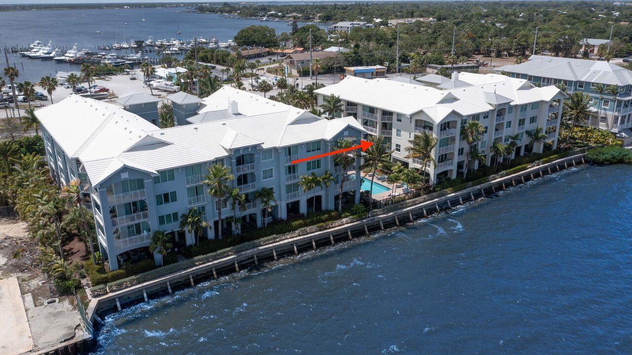 An aerial view of a multi-story waterfront apartment complex with a pool and palm trees — 275 NW Flagler Avenue # 205, Stuart FL 34994, STUART, FL