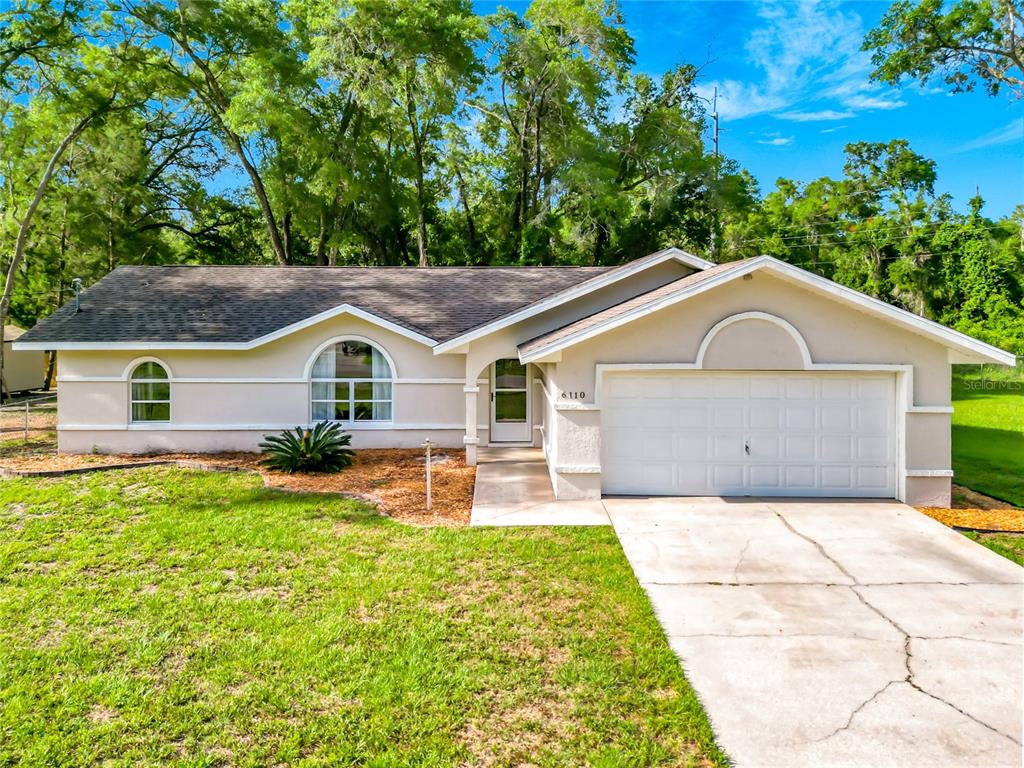 A single-story house with a beige stucco exterior, a two-car garage, and arched windows — 6110 E WINGATE STREET, INVERNESS, FL
