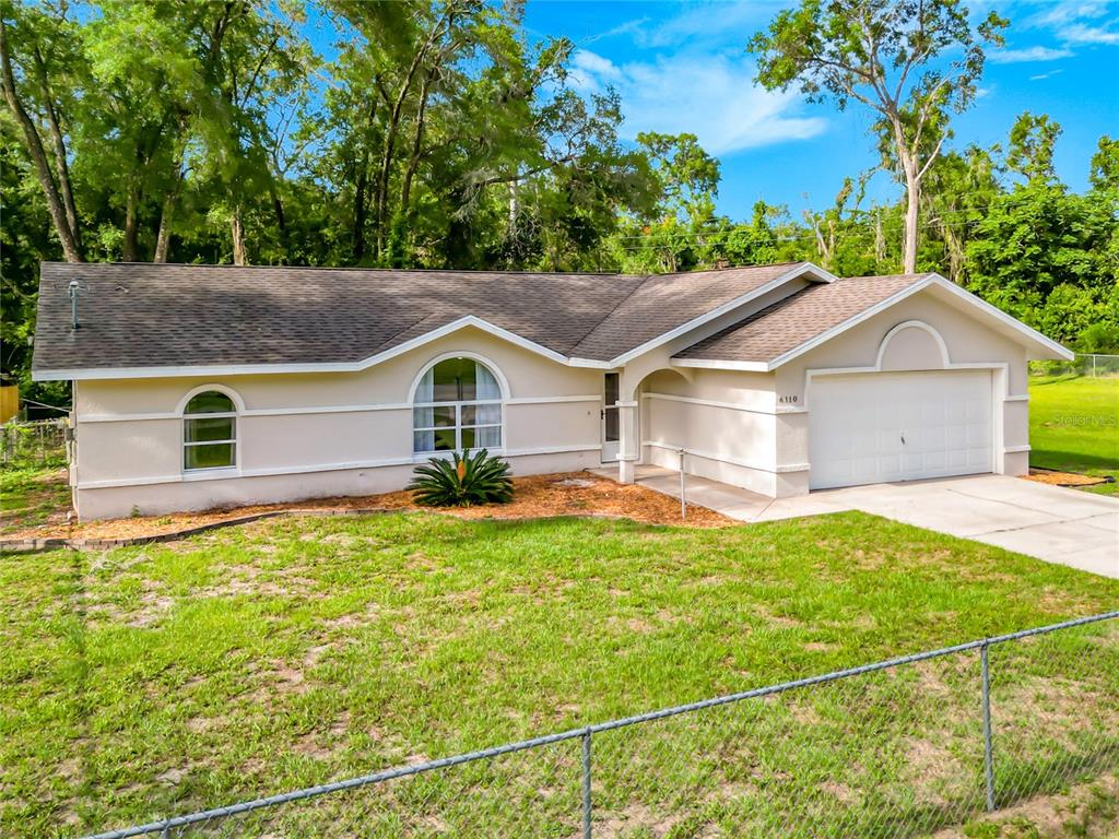 A single-story house with a beige stucco exterior, a two-car garage, and arched windows — 6110 E WINGATE STREET, INVERNESS, FL