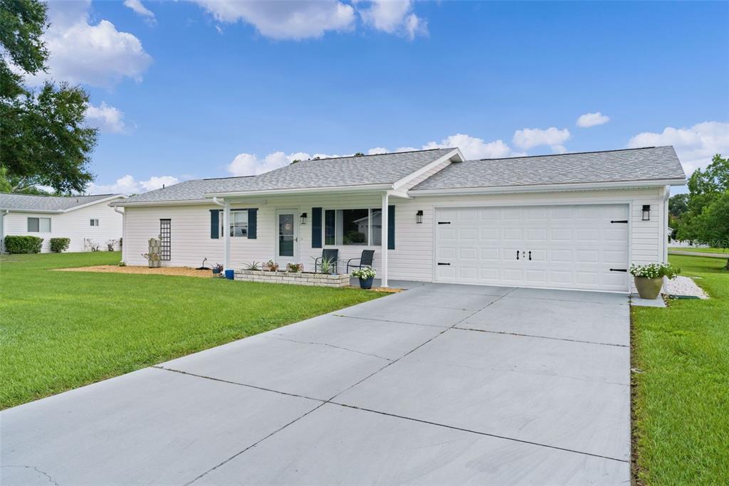 A white single-story house features a gray shingled roof, a two-car garage, and a concrete driveway — 10591 SE 178TH STREET, SUMMERFIELD, FL