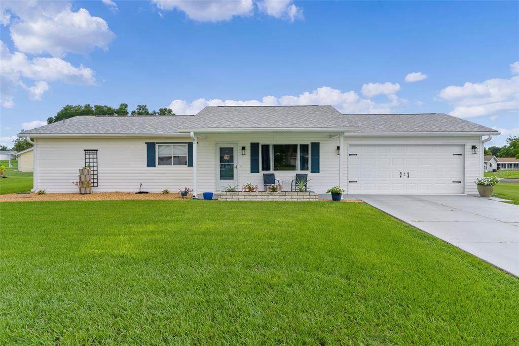 A single-story white house with blue shutters, a two-car garage, and a front lawn — 10591 SE 178TH STREET, SUMMERFIELD, FL