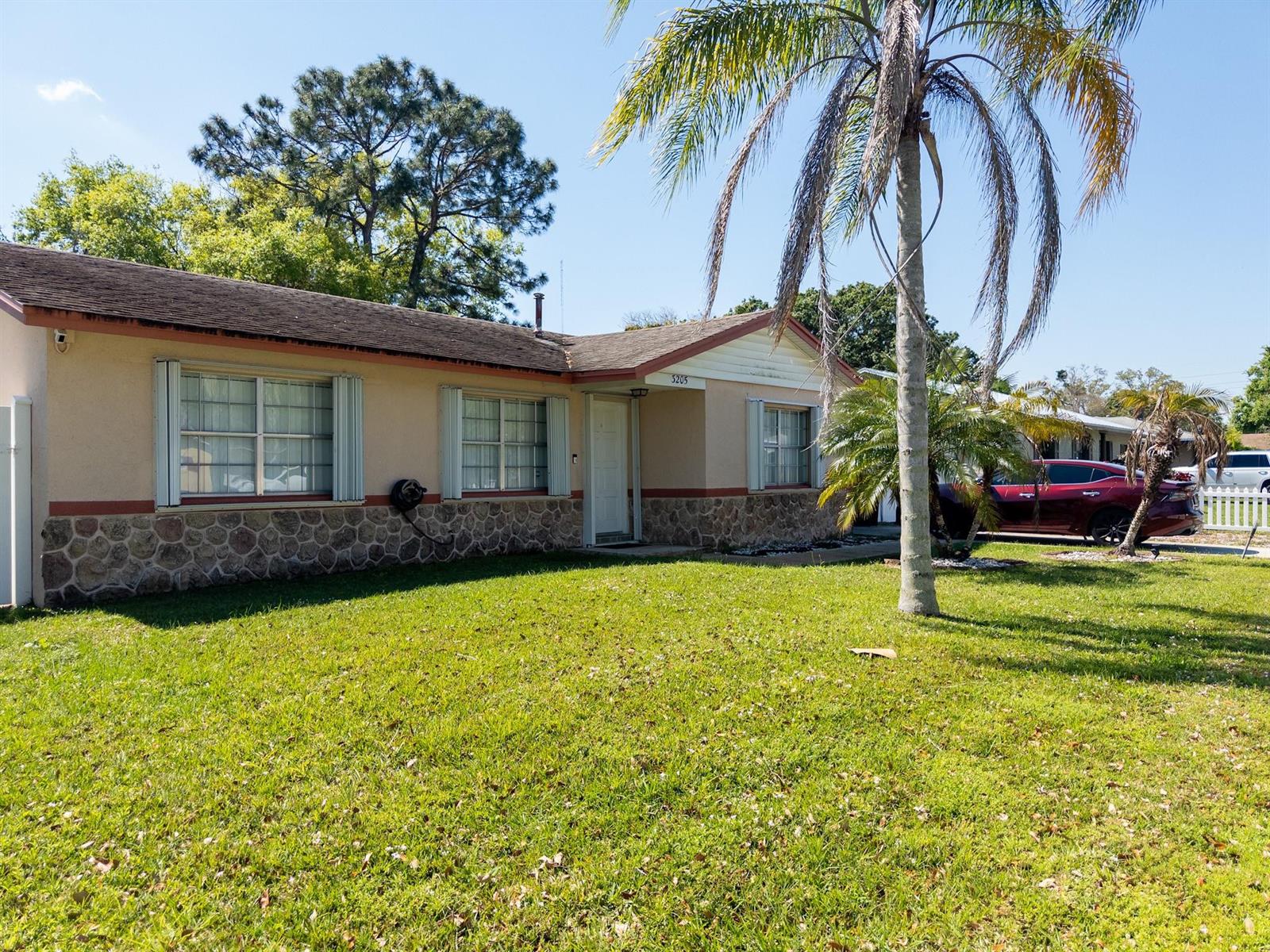 A single-story house with a stone facade, tan stucco walls, and a palm tree in front — 3205 Hibiscus, Fort Pierce FL 34947, FORT PIERCE, FL