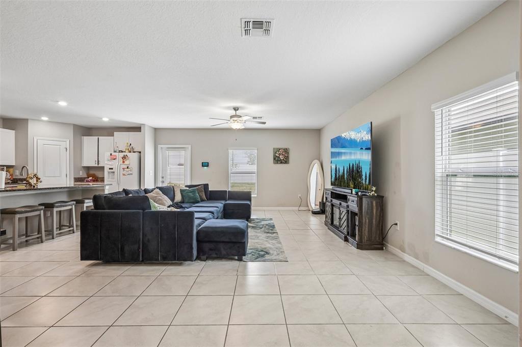 A living room features tile flooring, a large sectional sofa, and a television on a console — 10360 BLUE PLUME COURT, RIVERVIEW, FL