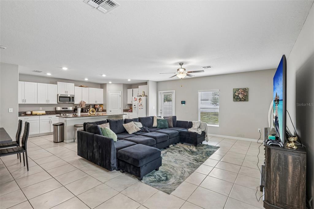 An open-concept living room and kitchen featuring a large sectional sofa and tile flooring — 10360 BLUE PLUME COURT, RIVERVIEW, FL
