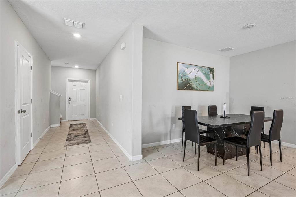 A dining area with a black marble table and chairs sits next to a tiled entryway — 10360 BLUE PLUME COURT, RIVERVIEW, FL