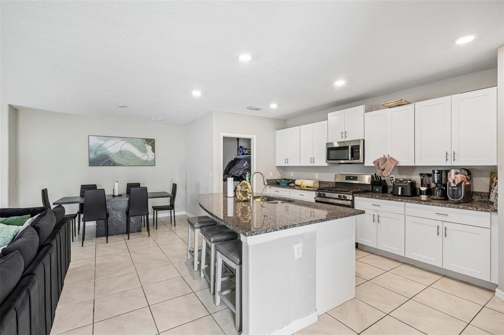 A kitchen with white cabinets, granite countertops, and a dining area with a black table — 10360 BLUE PLUME COURT, RIVERVIEW, FL