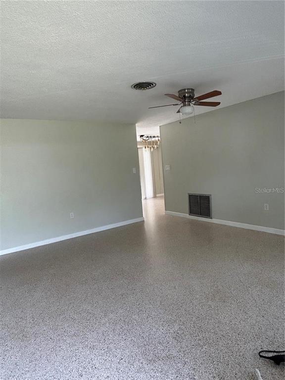 A living room with light gray walls, a ceiling fan, and speckled flooring — 819 E 13TH AVENUE, NEW SMYRNA BEACH, FL