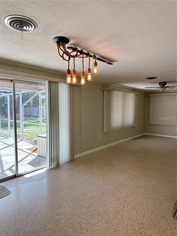 An interior living space features a unique rope chandelier, sliding glass doors, and carpeted floors — 819 E 13TH AVENUE, NEW SMYRNA BEACH, FL