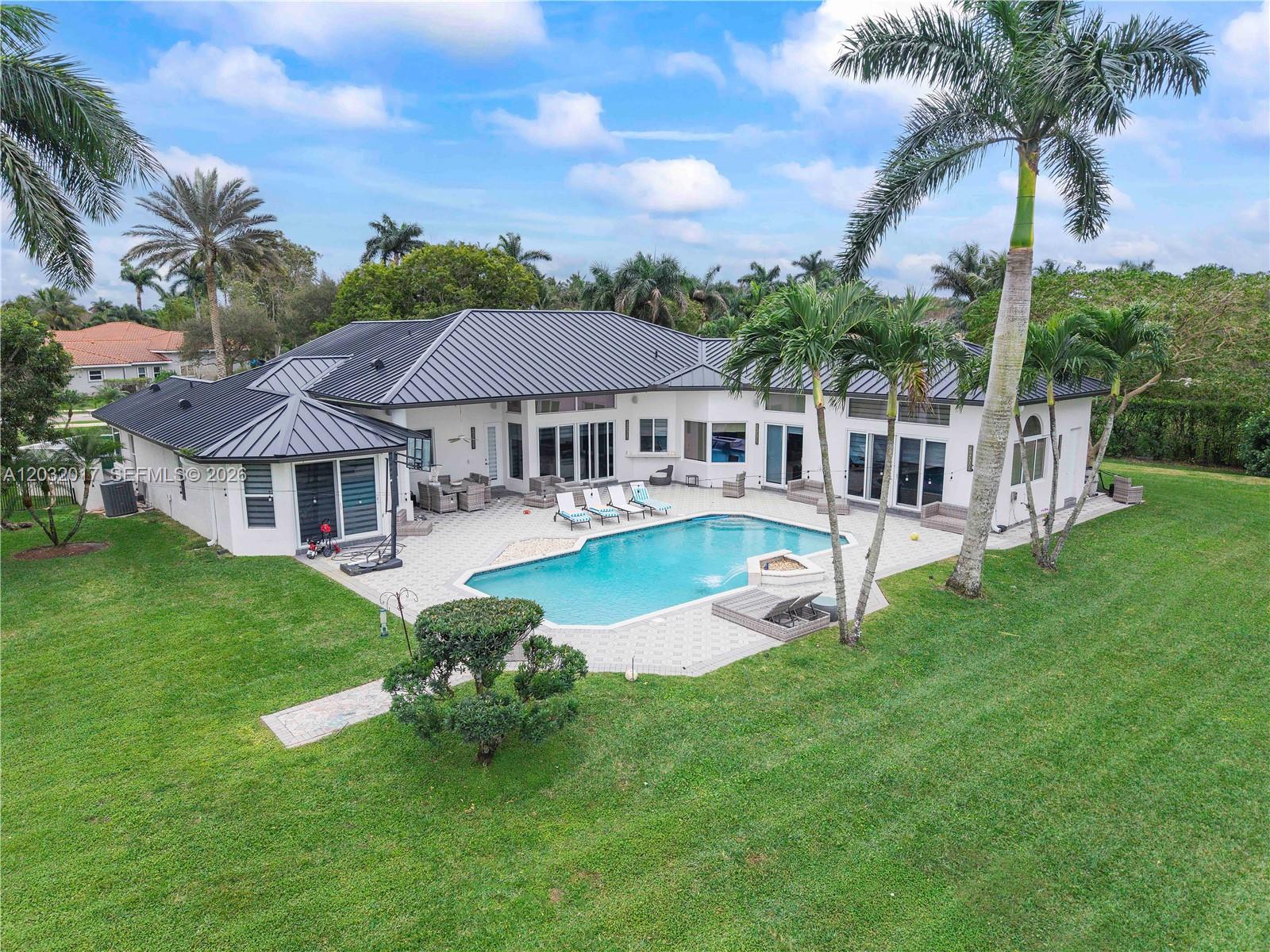 An aerial view of a house with a dark metal roof, pool, and palm trees — 2235 SW 105th Ter, Davie FL 33324, DAVIE, FL