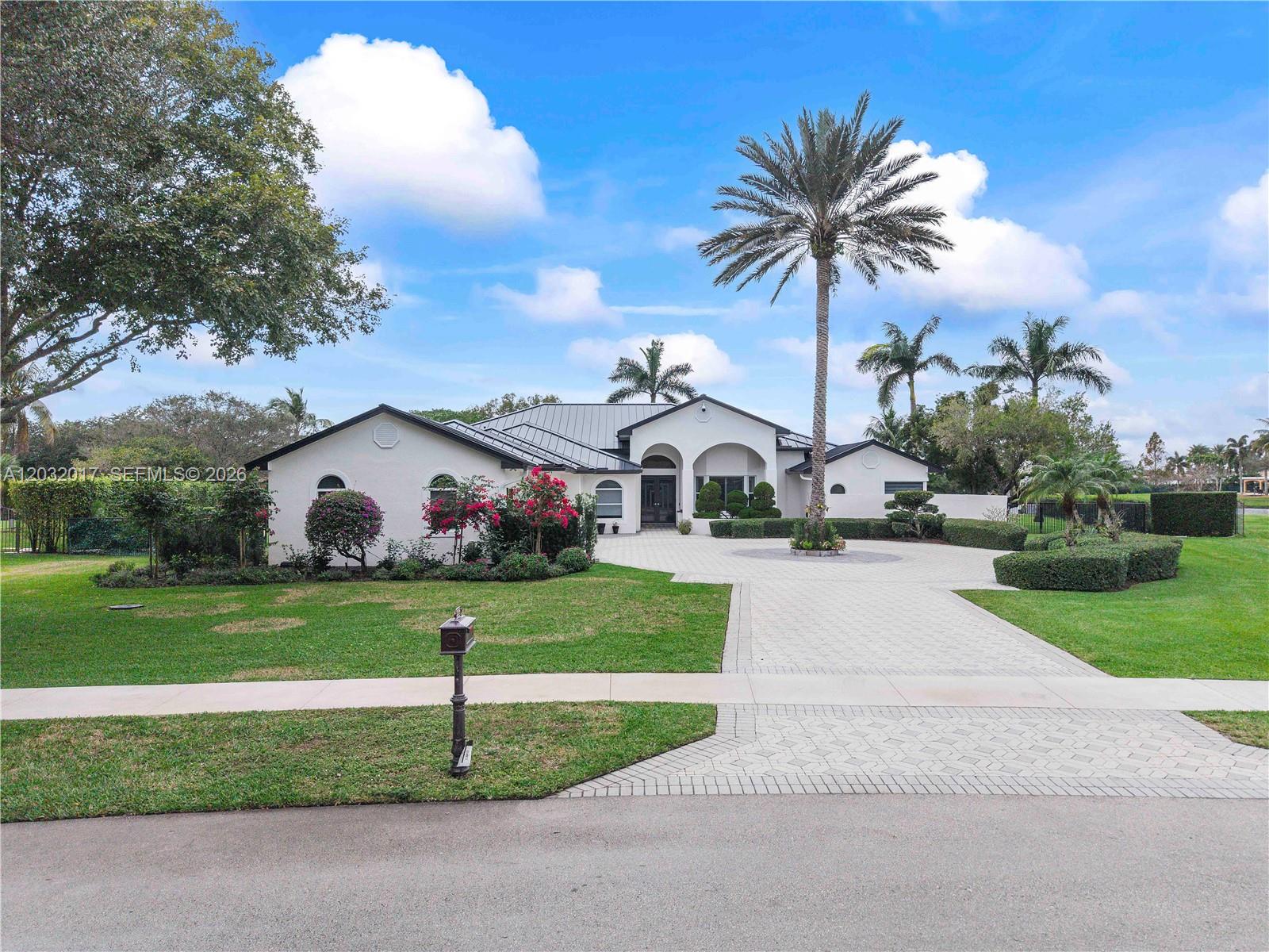 A white single-story house with a metal roof and a large circular paver driveway — 2235 SW 105th Ter, Davie FL 33324, DAVIE, FL