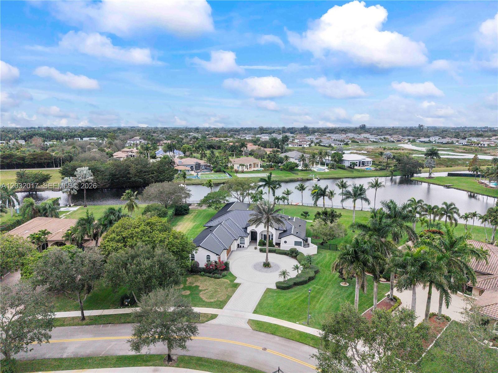 An aerial view shows a single-story house with a circular driveway and a backyard lake — 2235 SW 105th Ter, Davie FL 33324, DAVIE, FL