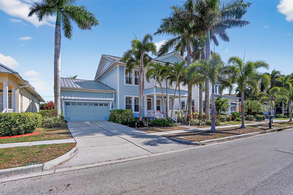 A blue two-story house with a metal roof and palm trees in the front yard — 416 MANNS HARBOR DRIVE, APOLLO BEACH, FL