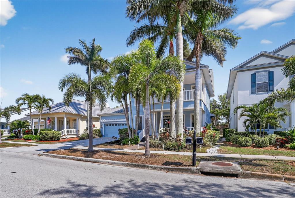 A blue two-story house with palm trees in the front yard on a sunny day — 416 MANNS HARBOR DRIVE, APOLLO BEACH, FL