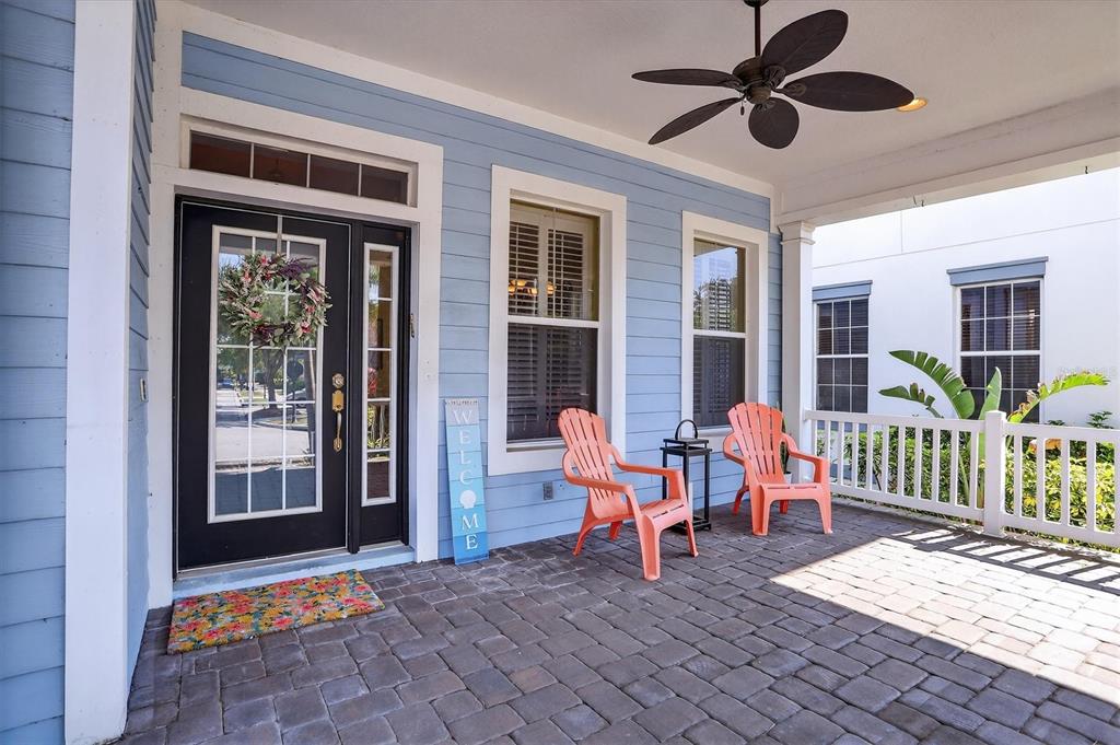 A covered front porch features light blue siding, a black front door, and two orange chairs — 416 MANNS HARBOR DRIVE, APOLLO BEACH, FL