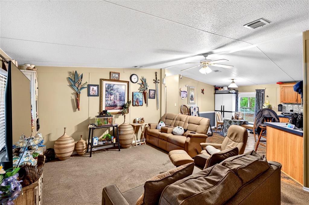 A living room with beige walls, carpeted flooring, a ceiling fan, and brown furniture — 1502 NE 644TH STREET, OLD TOWN, FL