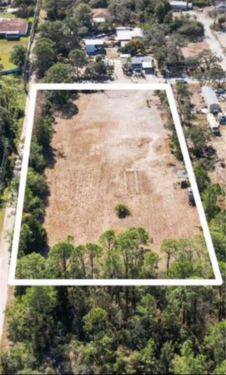 An aerial view shows a rectangular, cleared vacant lot surrounded by trees and nearby houses — 7435 TERRACE DRIVE, HUDSON, FL