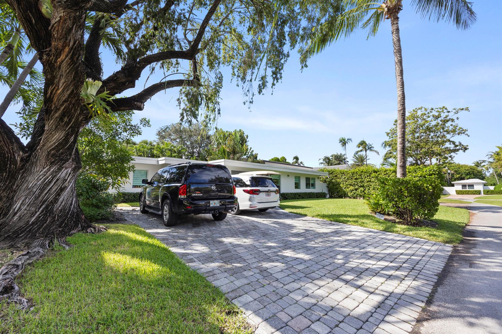 A paved driveway leads to a single-story house with two parked SUVs under large trees — 630 Allendale Road, Key Biscayne FL 33149, KEY BISCAYNE, FL
