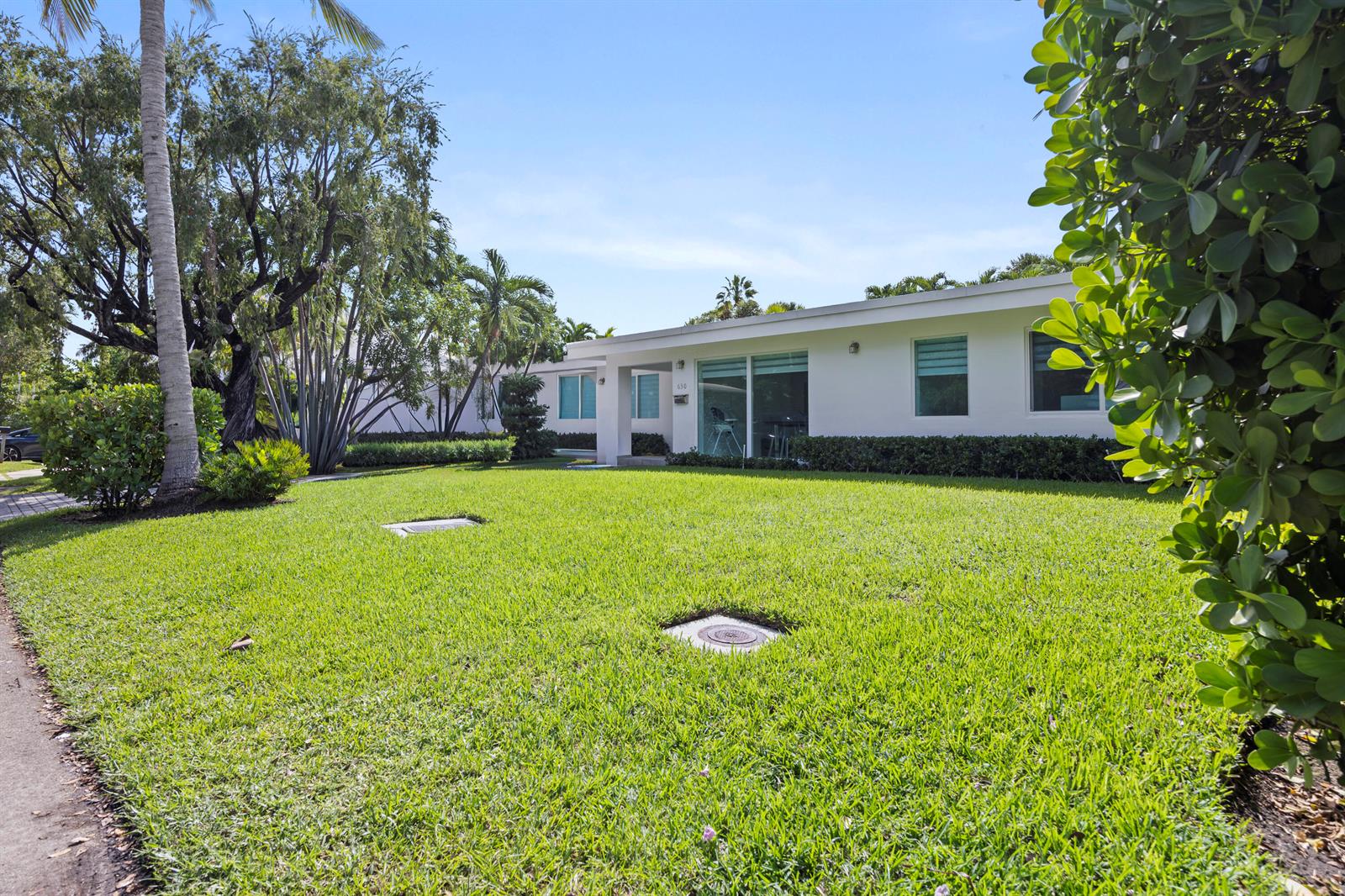 A white single-story house with a flat roof sits behind a large green lawn — 630 Allendale Road, Key Biscayne FL 33149, KEY BISCAYNE, FL