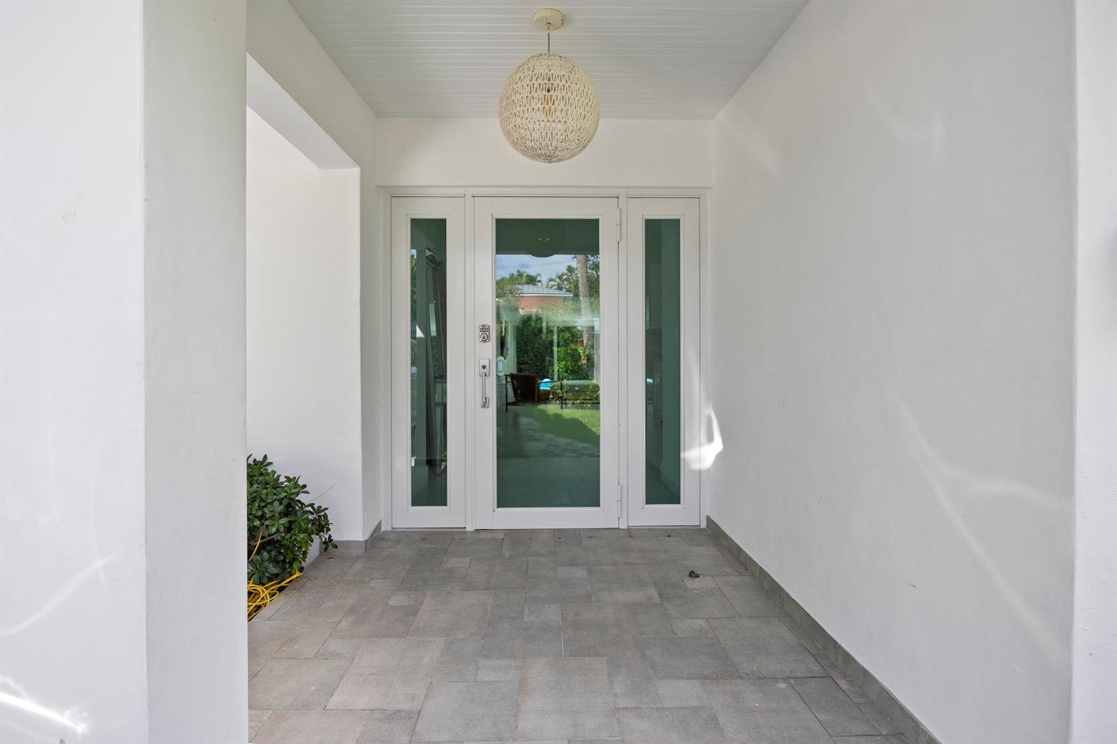 A white front door with glass panels and a pendant light on a tiled porch — 630 Allendale Road, Key Biscayne FL 33149, KEY BISCAYNE, FL