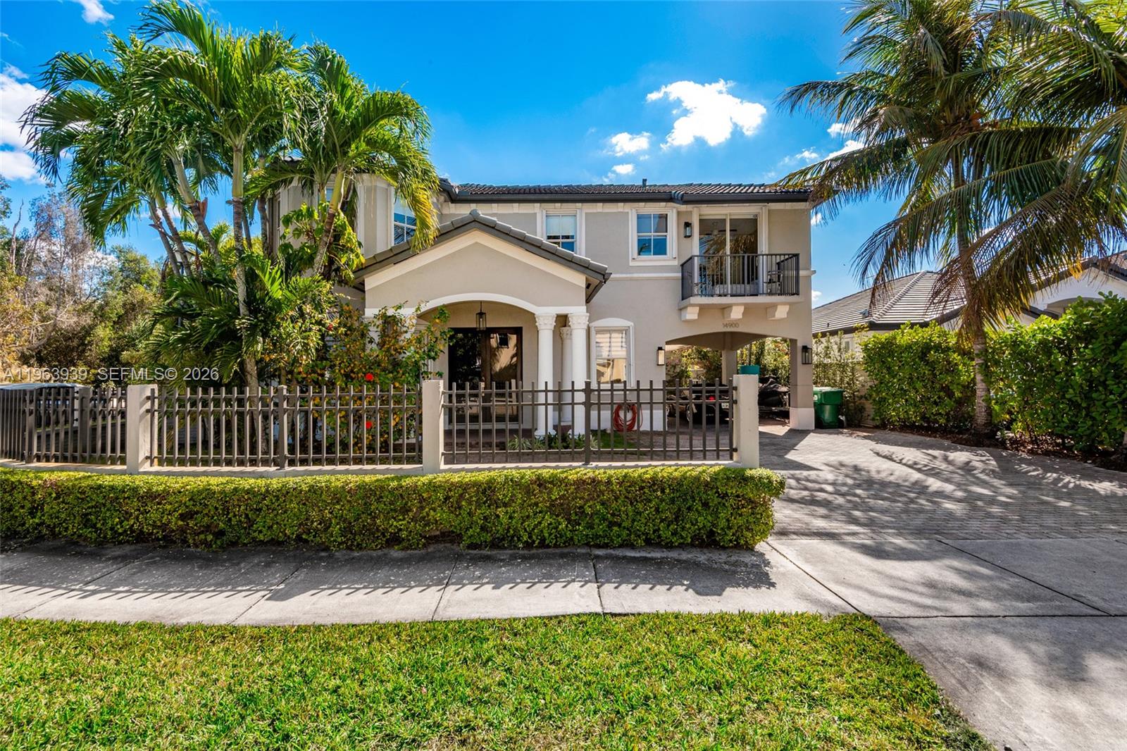 A two-story house features a gated front yard, a covered entryway, and a second-floor balcony — 14900 SW 10th St, Miami FL 33194, MIAMI, FL