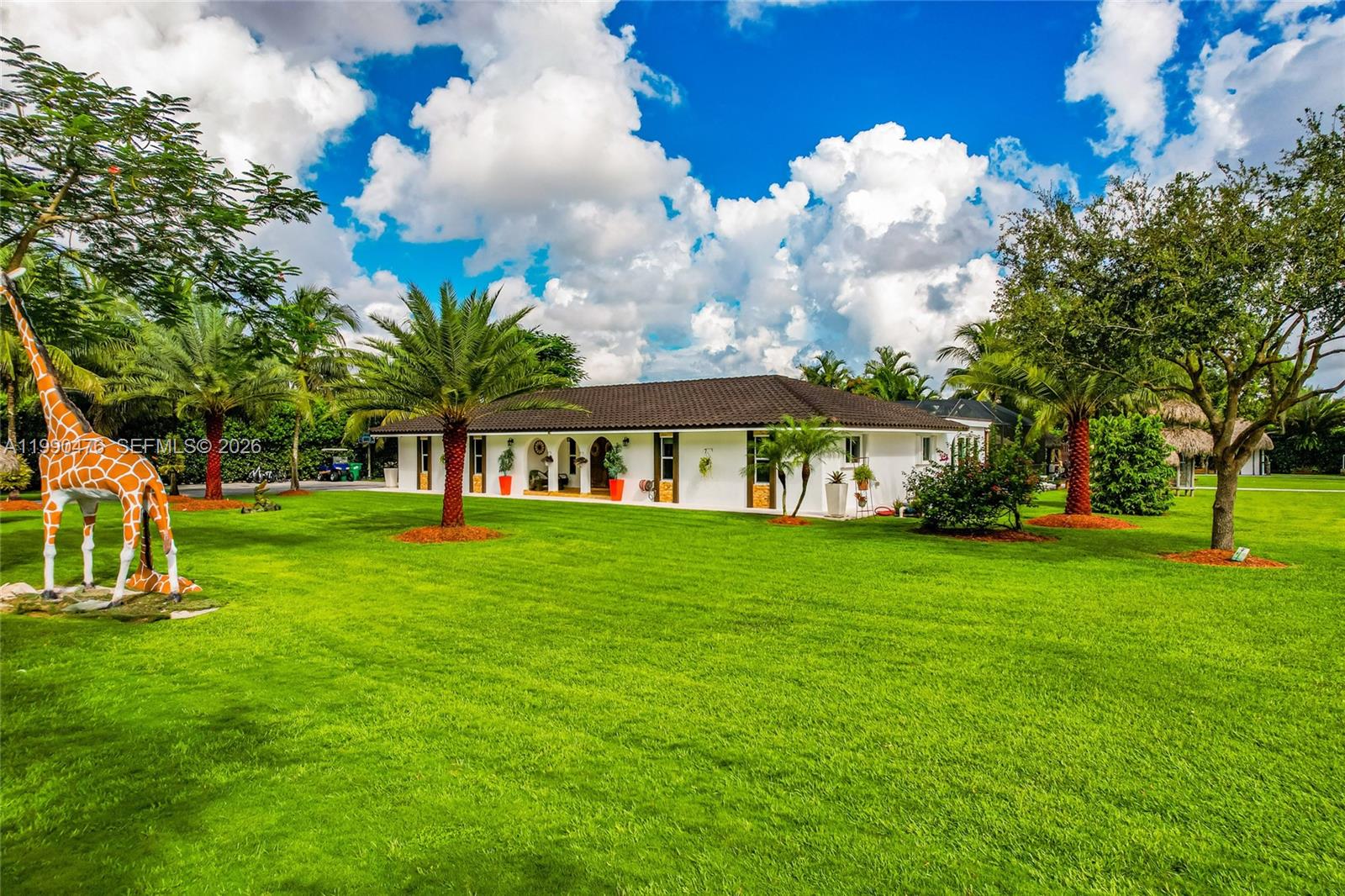 A white single-story house with a dark tile roof sits on a large grassy lawn — 18851 SW 218th St, Miami FL 33170, MIAMI, FL