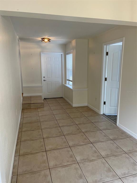 An entryway features light-colored tile flooring, a white front door, and a nearby interior door — 1914 W AILEEN STREET, TAMPA, FL