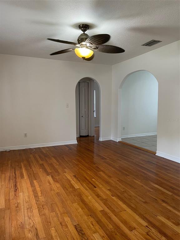 A living room features hardwood floors, a ceiling fan, and two arched doorways — 1914 W AILEEN STREET, TAMPA, FL