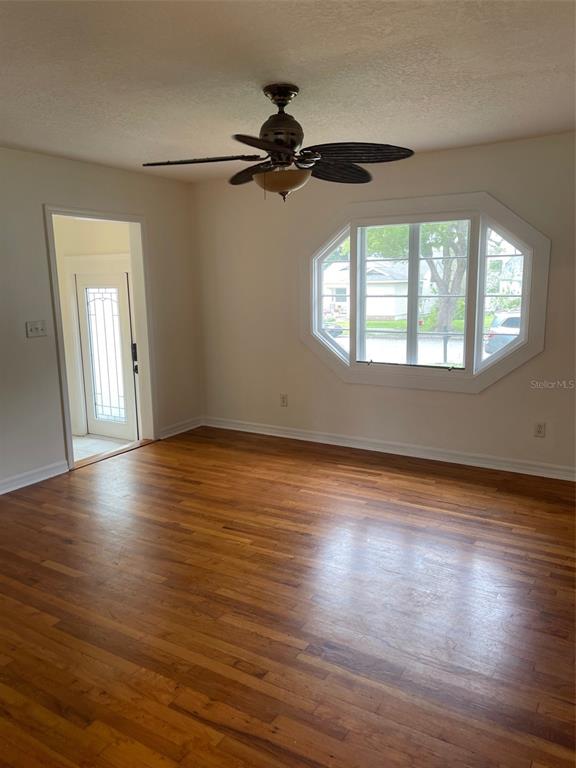 A room with hardwood floors, a ceiling fan, and a large bay window — 1914 W AILEEN STREET, TAMPA, FL