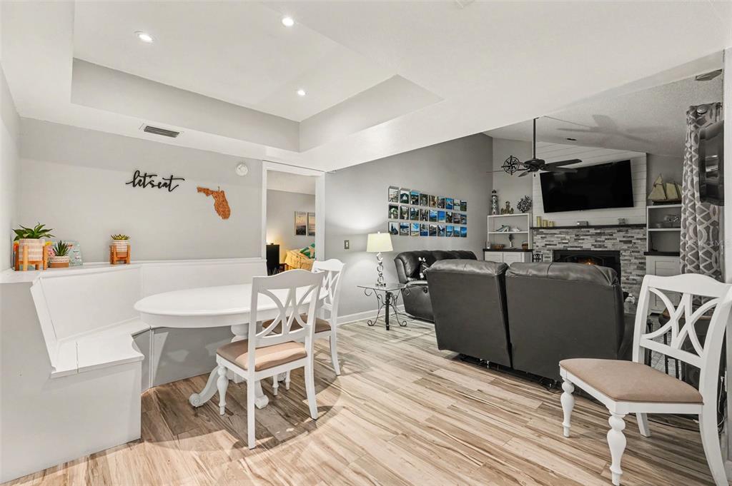 A dining area with a built-in bench and white chairs opens into a living room — 9303 ROLLING RIDGE PLACE, TAMPA, FL
