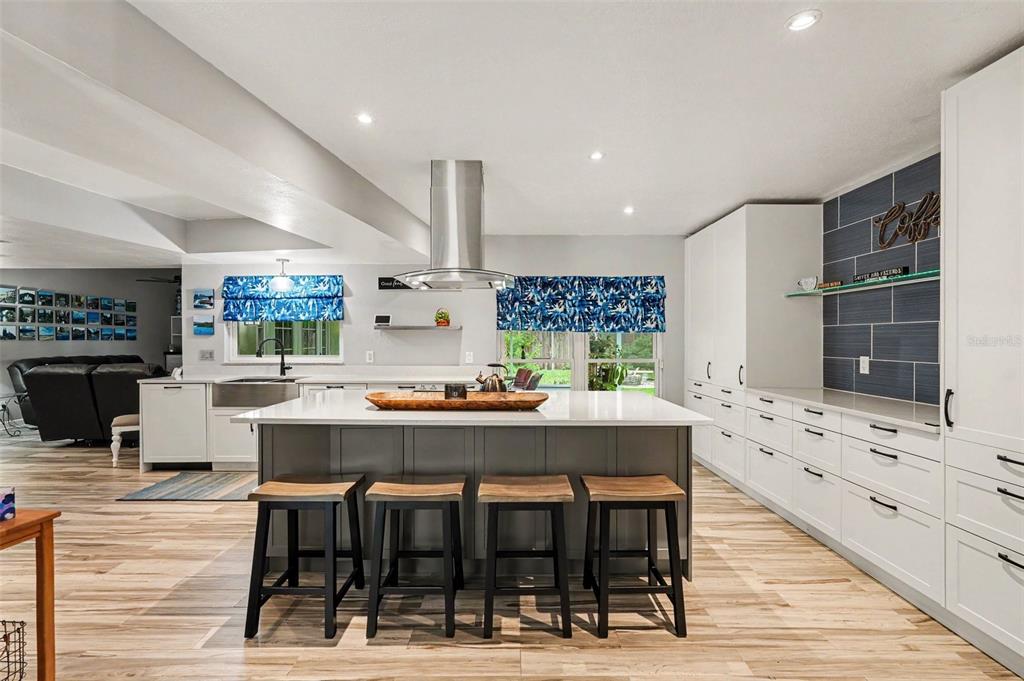 A modern kitchen features a large gray island with bar stools and white cabinetry — 9303 ROLLING RIDGE PLACE, TAMPA, FL
