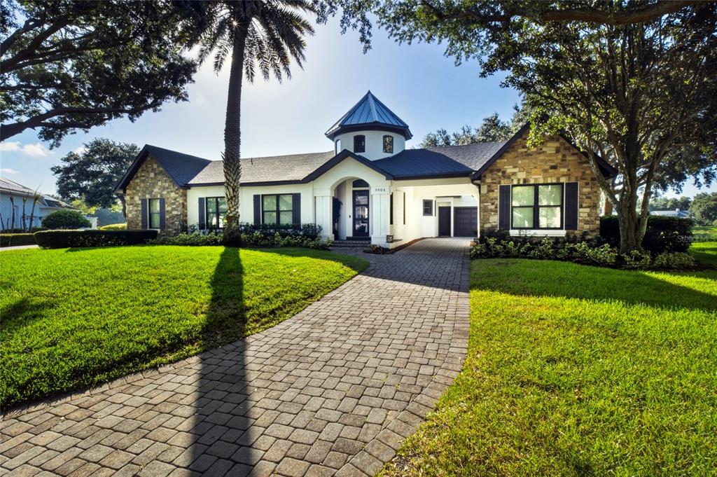 A single-story house with a stone facade, a central turret, and a paved driveway — 9904 BRENTFORD COURT, WINDERMERE, FL