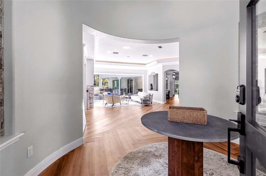 A foyer with a round table and wood flooring opens into a bright living room — 9904 BRENTFORD COURT, WINDERMERE, FL