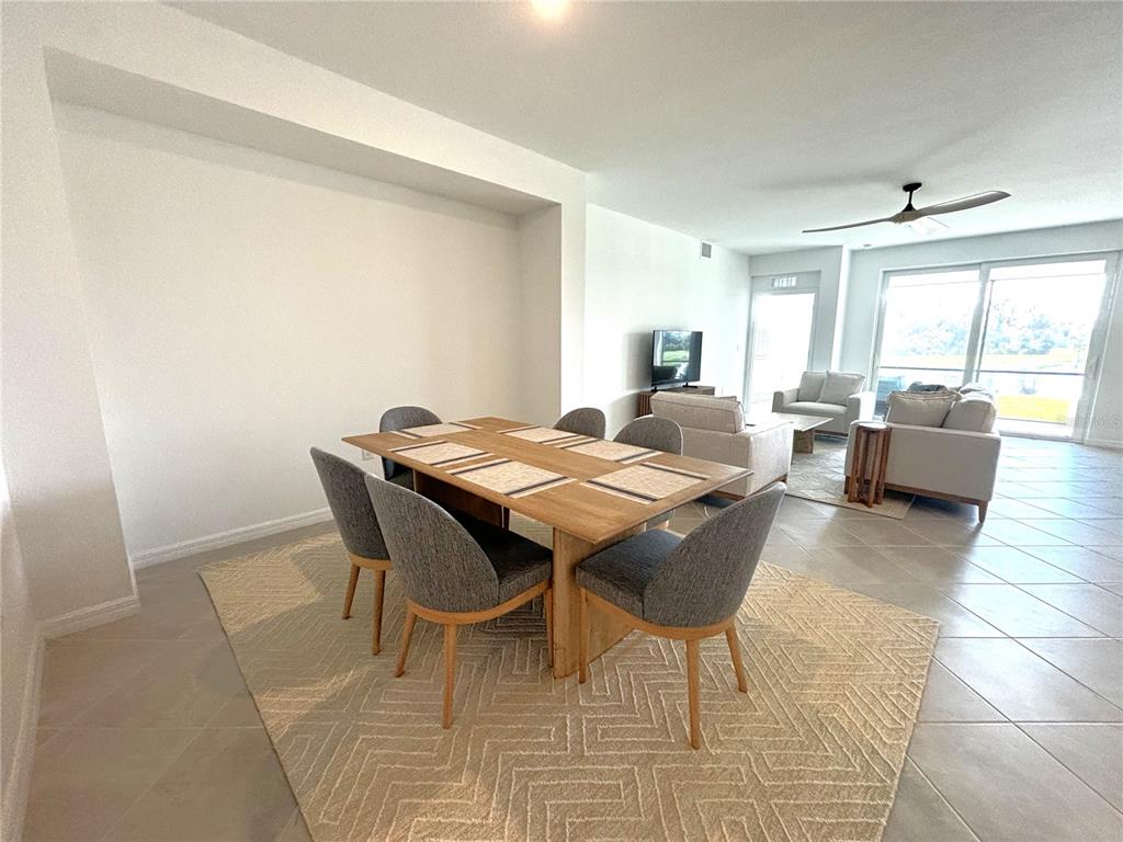 A dining area with a wooden table and chairs sits on a patterned area rug — 17620 BORACAY COURT UNIT 102, VENICE, FL