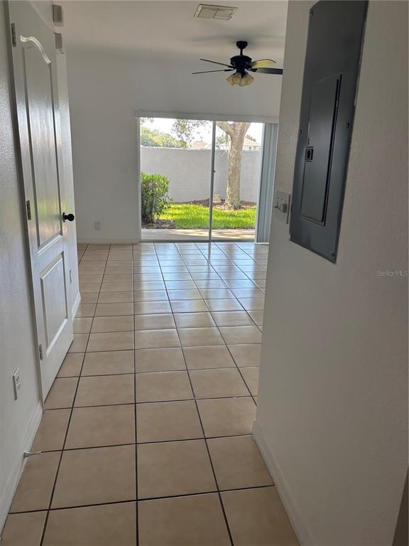 A tiled hallway leads to a living area with a ceiling fan and sliding glass doors — 10922 SAVANNAH WOOD DRIVE UNIT 141, ORLANDO, FL