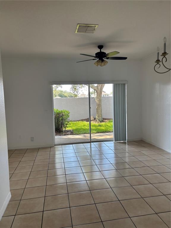 A room with light-colored tile flooring, a ceiling fan, and sliding glass doors to a yard — 10922 SAVANNAH WOOD DRIVE UNIT 141, ORLANDO, FL