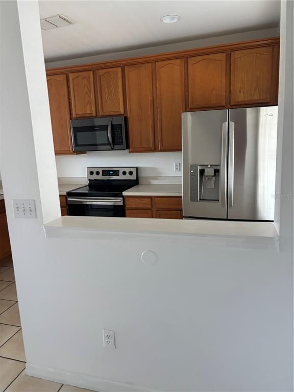 A kitchen features wood cabinets, stainless steel appliances, and a white pass-through wall — 10922 SAVANNAH WOOD DRIVE UNIT 141, ORLANDO, FL