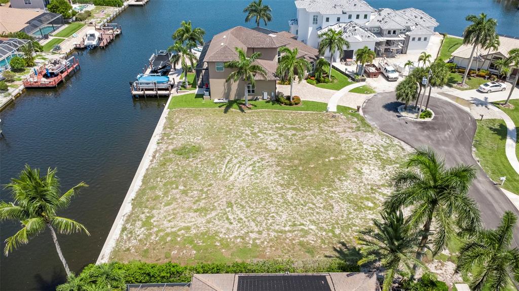 An aerial view shows a vacant waterfront lot next to a large house and canal — 375 WALES COURT, MARCO ISLAND, FL