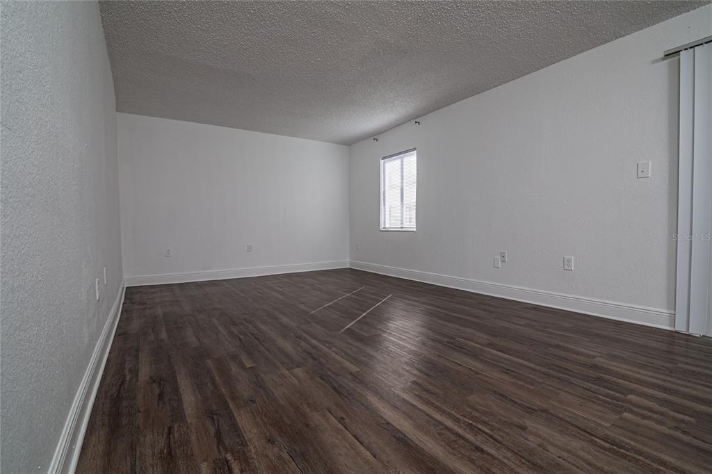 An empty room with white walls, dark wood-look flooring, and a single window — 4789 S TEXAS AVENUE UNIT A, ORLANDO, FL