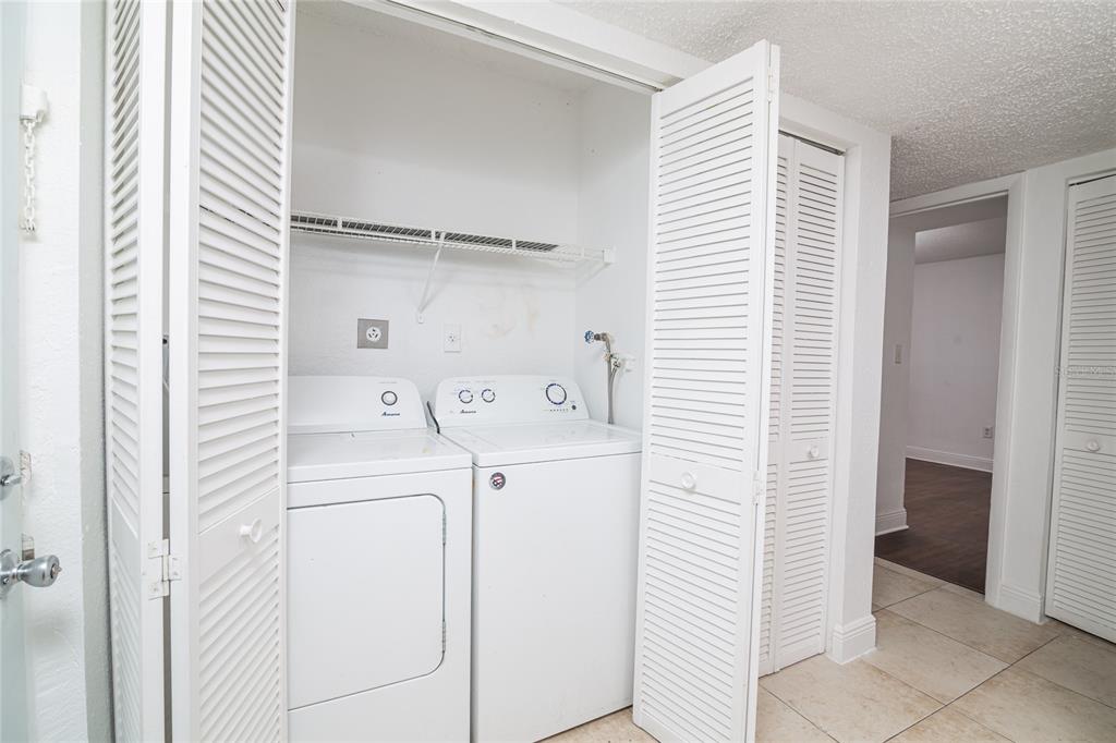 A laundry closet with a white washer and dryer set behind louvered doors — 4789 S TEXAS AVENUE UNIT A, ORLANDO, FL