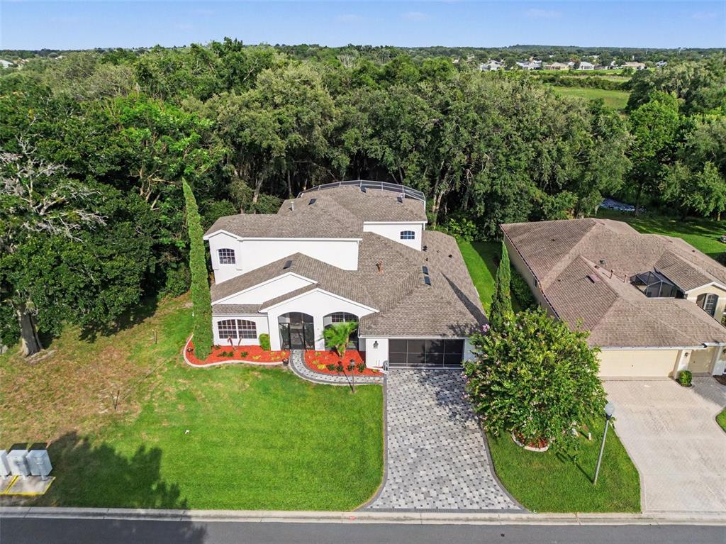 An aerial view of a two-story house with a paver driveway and a backyard pool — 5384 AURORA DRIVE, LEESBURG, FL