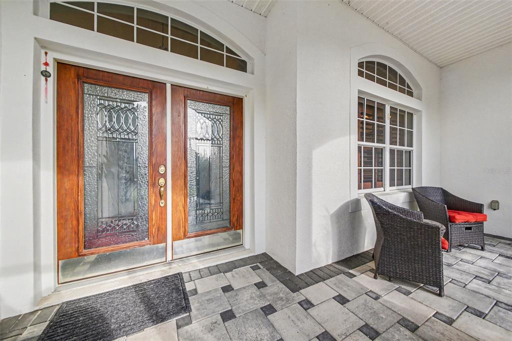 A covered front porch features double wood doors with glass inserts and two wicker chairs — 5384 AURORA DRIVE, LEESBURG, FL