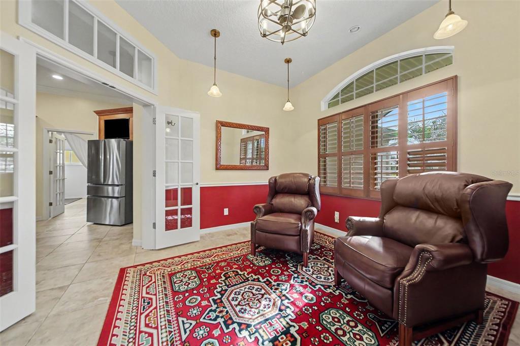 A room with two leather armchairs, a red patterned rug, and red wainscoting — 5384 AURORA DRIVE, LEESBURG, FL