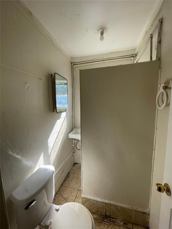 A small bathroom features a toilet, a wall-mounted sink, and a shower partition — 131 B STREET UNIT 2, LAKE WALES, FL