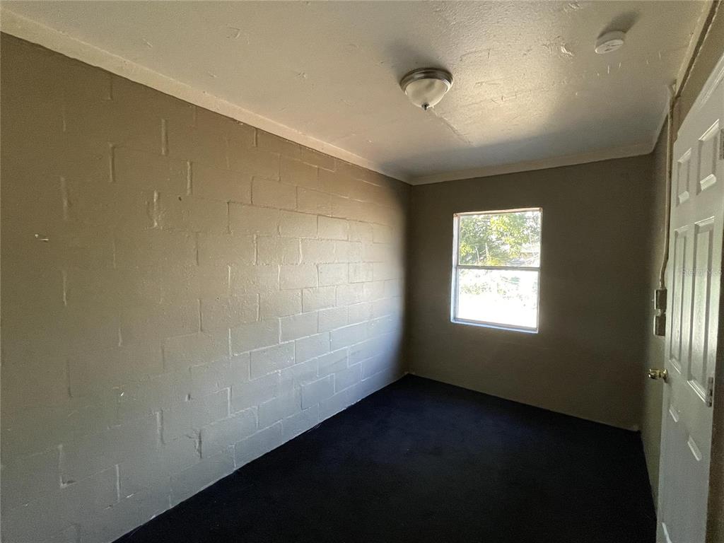 A small room features dark carpet, painted concrete block walls, and a single window — 131 B STREET UNIT 2, LAKE WALES, FL