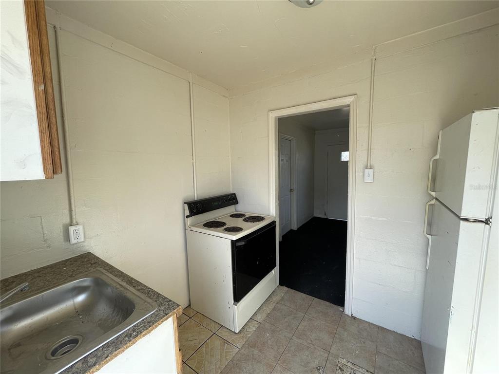 A kitchen features a stainless steel sink, a white electric stove, and a white refrigerator — 131 B STREET UNIT 2, LAKE WALES, FL