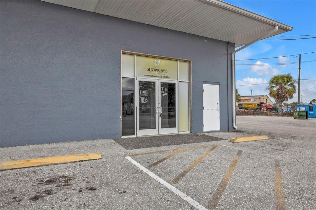 The exterior of a gray commercial building features a glass entrance and a white door — 4694 TAMIAMI TRAIL, PUNTA GORDA, FL
